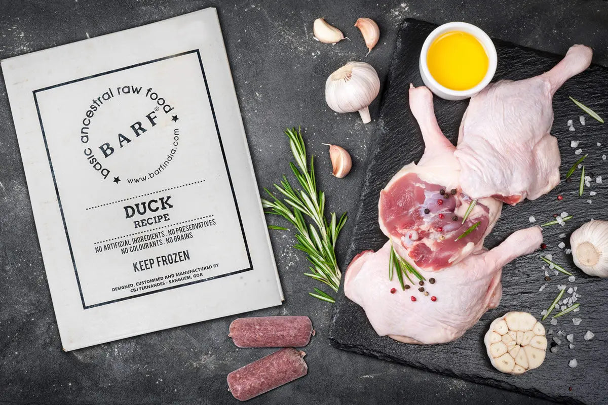 Two raw free-range duck legs with herbs, garlic, oil, and spices beside a www.barfindia.com Raw Dog Food - Duck Recipe - 4kgs pack, all arranged on a dark surface.
