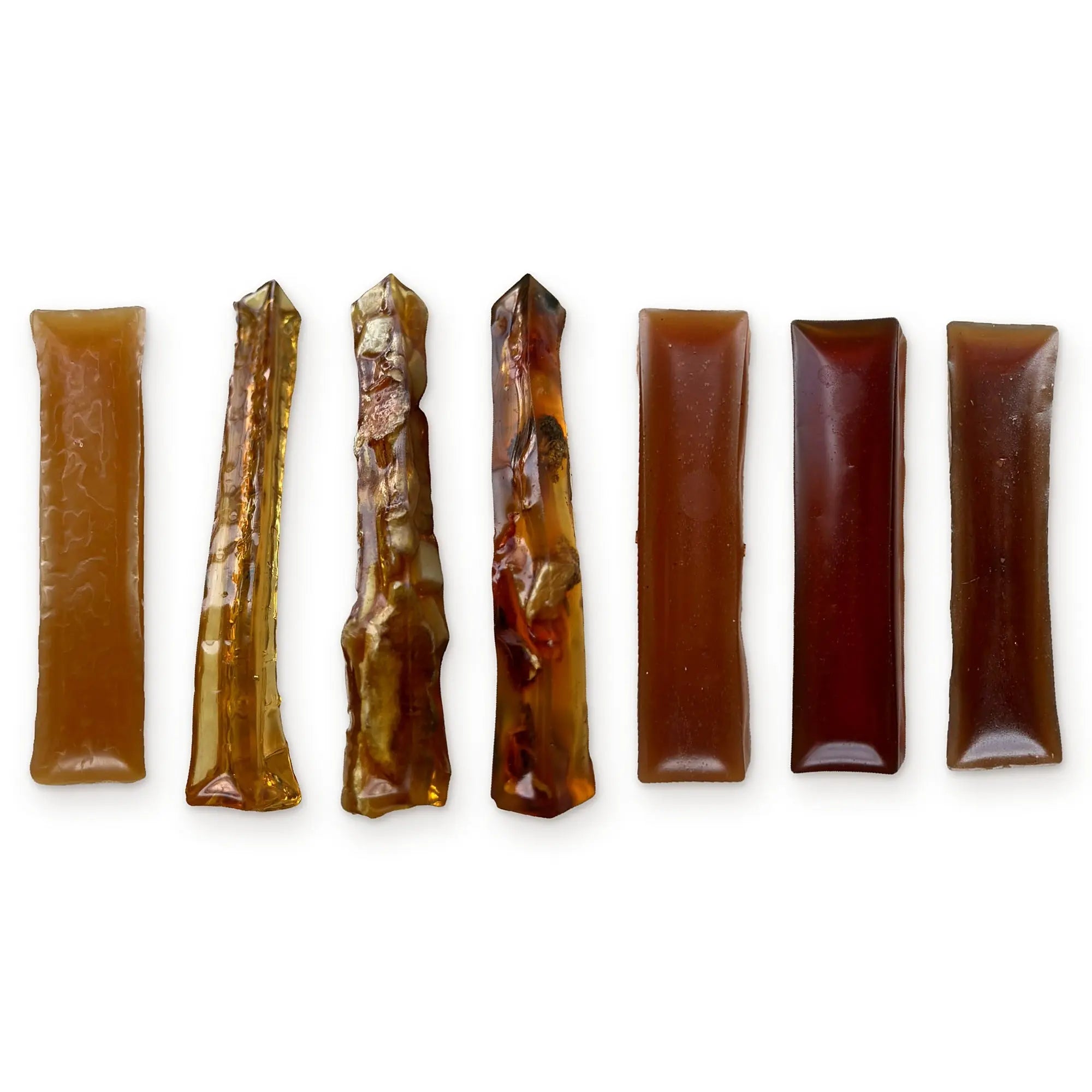 Seven bone broth hard chews for dogs lined up on white, from pale golden to deep mahogany. BARF INDIA