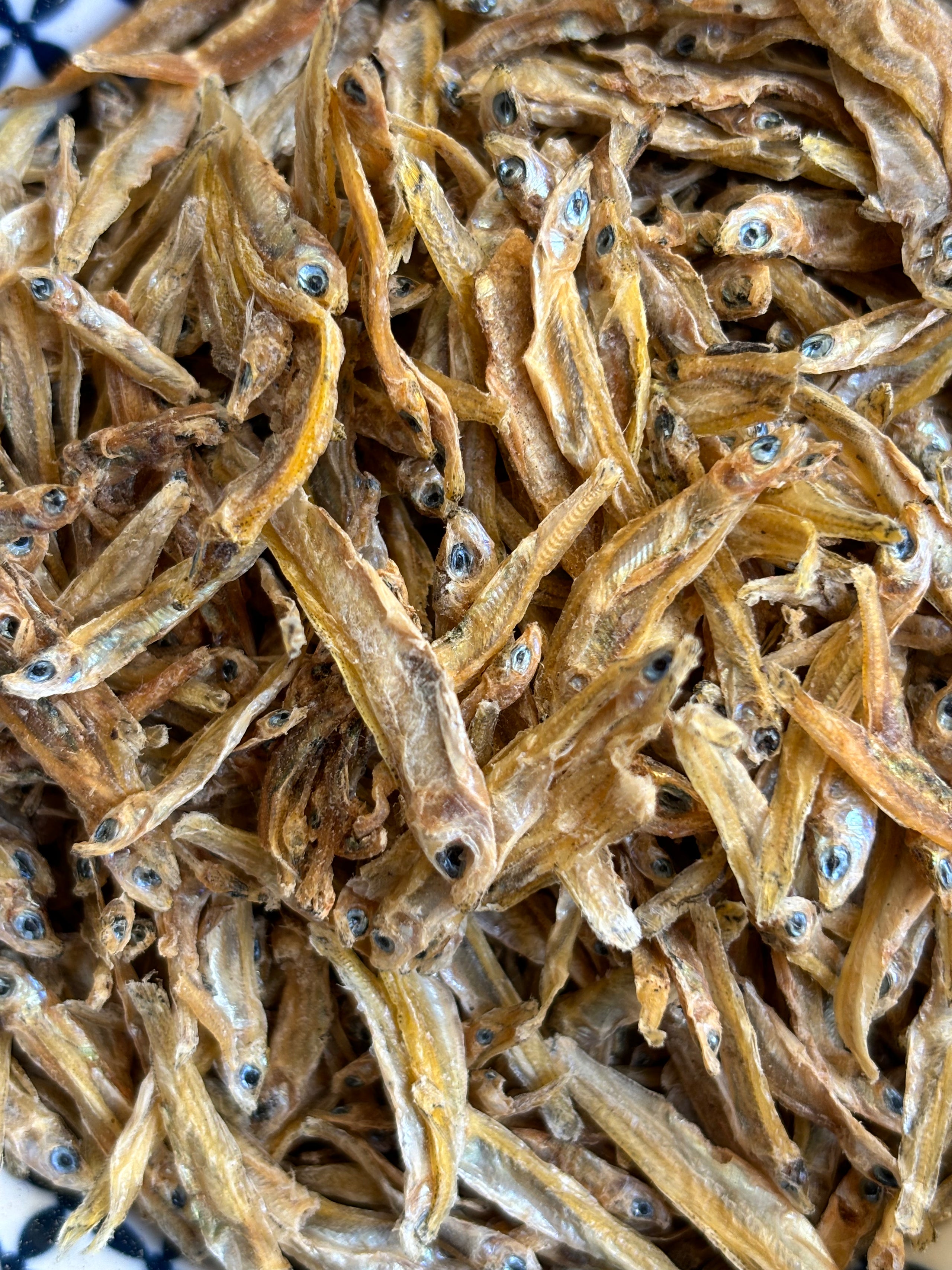 A close-up of Dog Treats Natural Omega 3 - Dehydrated Anchovies (100 gms) by www.barfindia.com shows whole anchovies with eyes and fins, tightly packed—ideal natural, flavorful snacks for your dog.