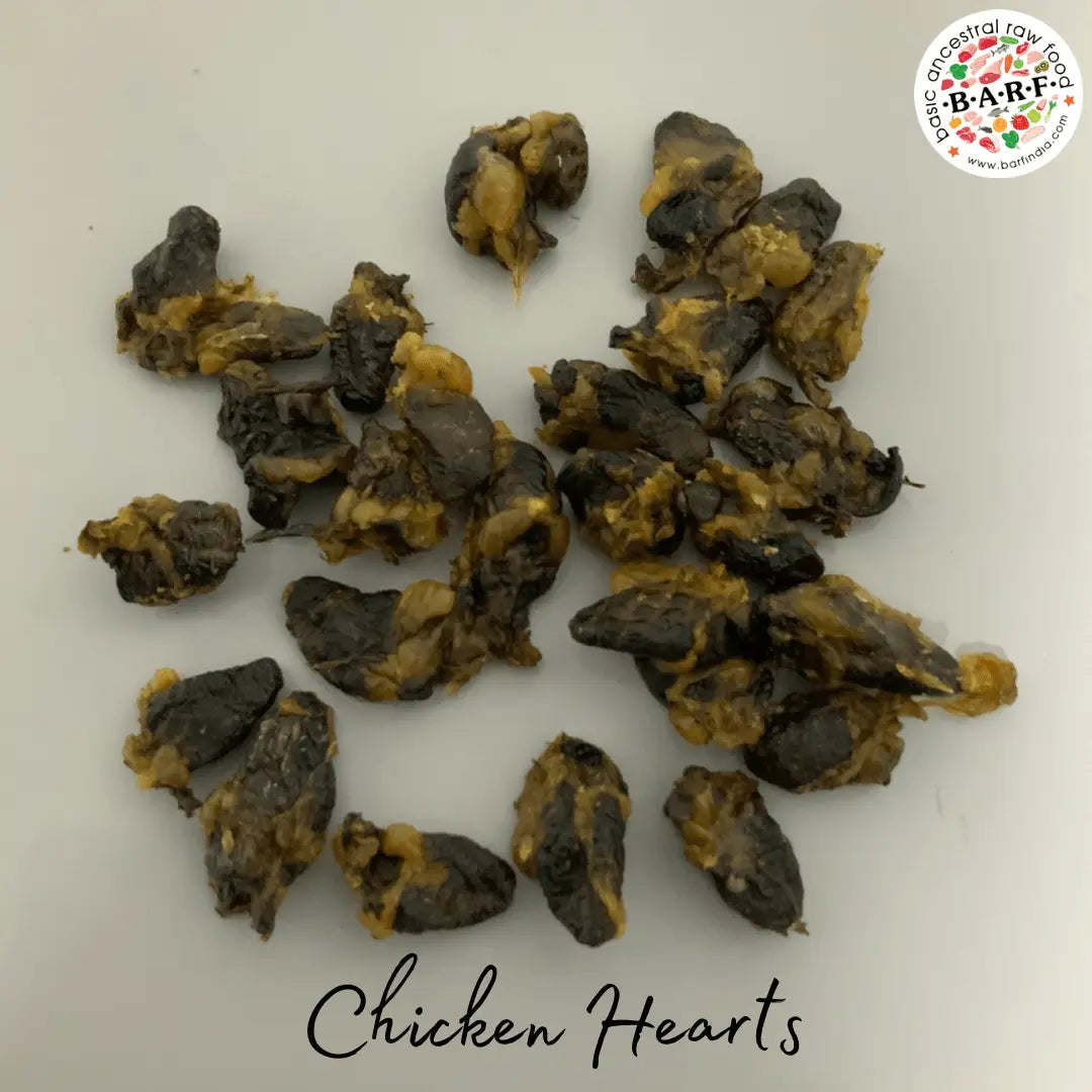 A pile of small, dark, slightly yellowish Dehydrated Chicken Hearts - 60gms is spread on a white surface. 
