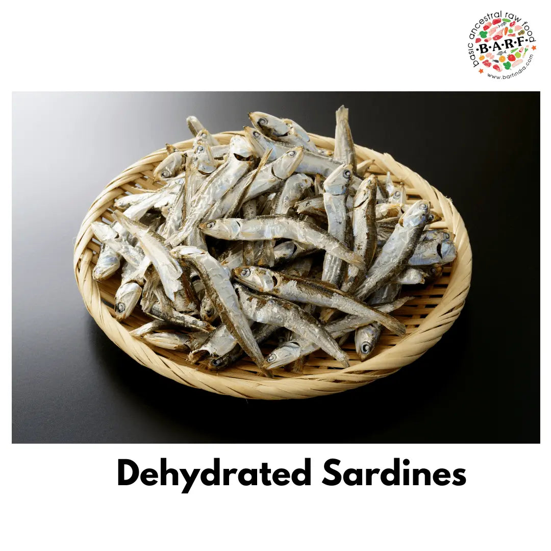 A round wicker basket holds many dehydrated sardines (Dog Treats - Dehydrated Sardines - 100 gms pack) atop a dark surface. 