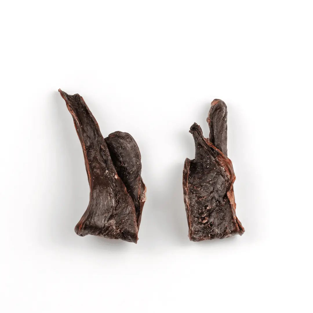 Two pieces of dehydrated pork hearts from www.barfindia.com, dark brown and irregularly shaped, are displayed on a white background—ideal as single-ingredient dog treats. Product: Dog Treats - Dehydrated Pork Hearts - 60 gms.
