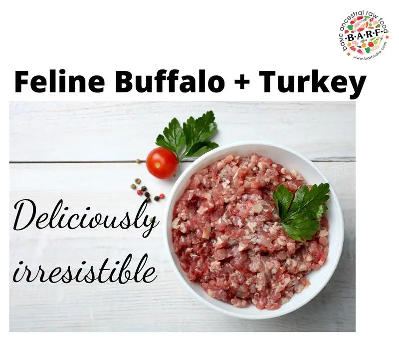 A bowl of Raw Cat Food – High-Protein Buffalo & Turkey Blend from www.barfindia.com, topped with parsley, a cherry tomato, and peppercorns on a white wooden surface. Text: Deliciously irresistible.